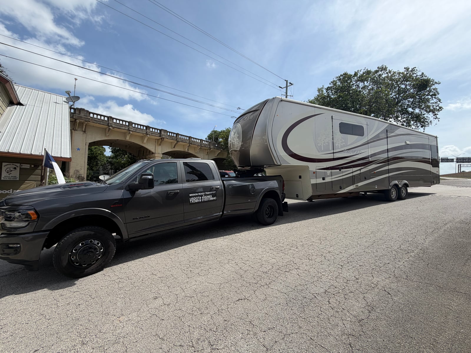 Mission Ready Transport truck towing a fifth wheel through a small town