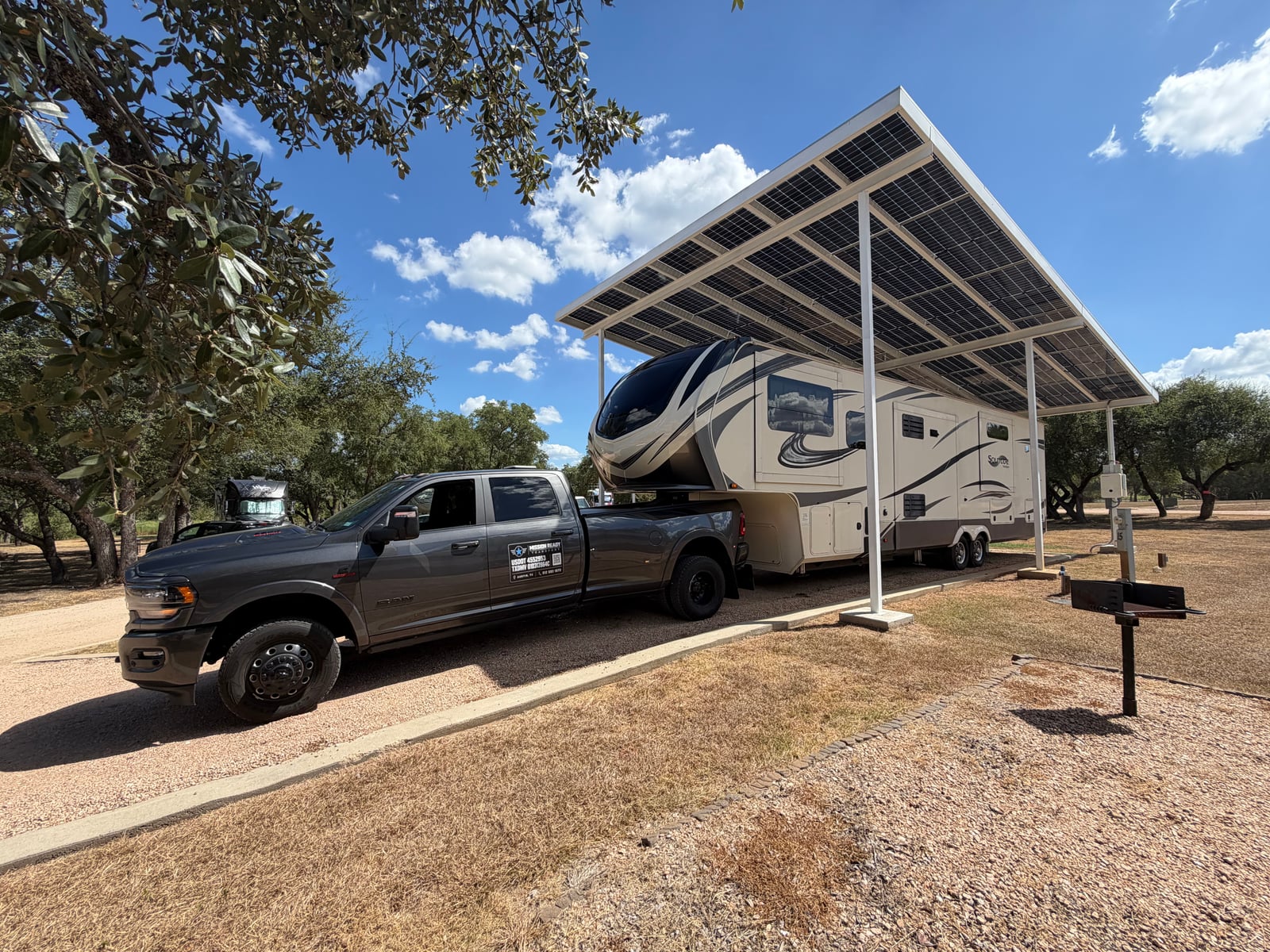 Mission Ready Transport truck with a fifth wheel parked under a solar canopy at an RV park