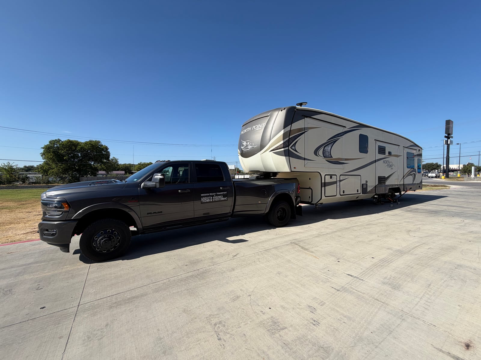 Mission Ready Transport truck towing a fifth wheel across a concrete lot
