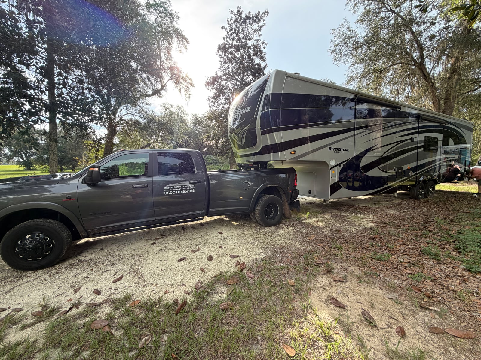 Mission Ready Transport truck maneuvering a fifth wheel into a shaded, wooded site