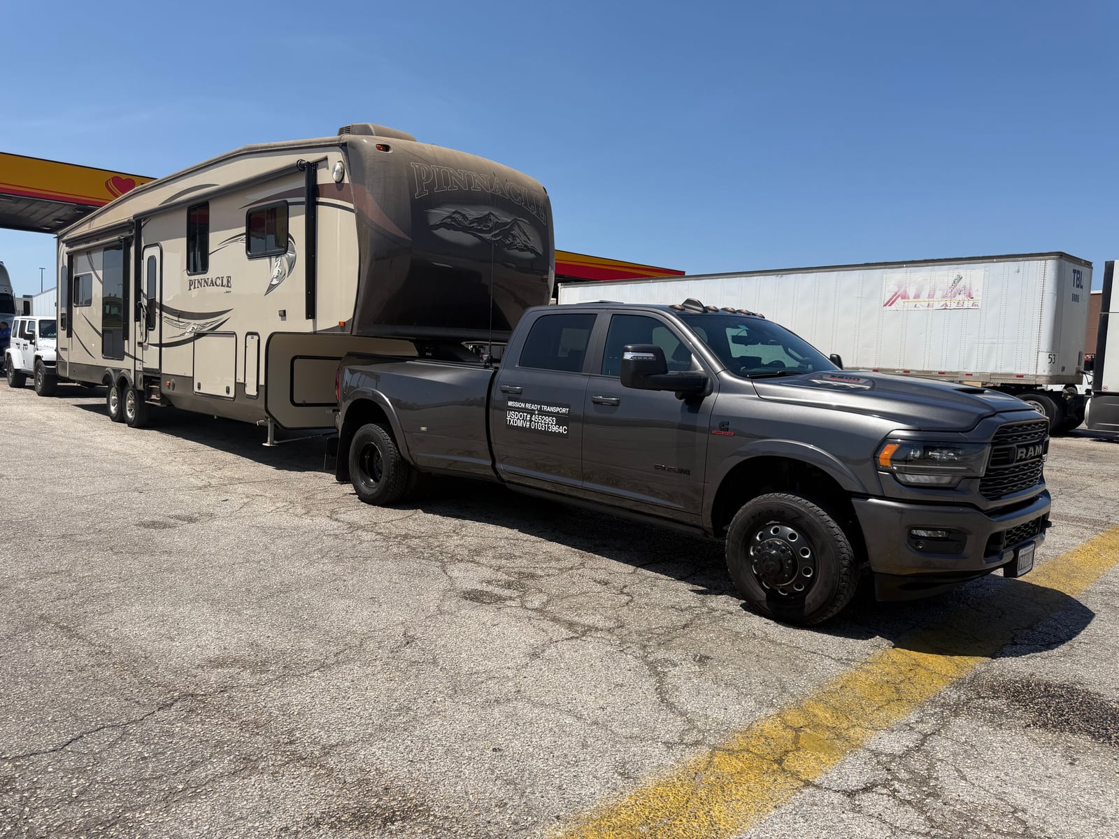 Mission Ready Transport truck towing a Pinnacle fifth wheel at a fuel stop